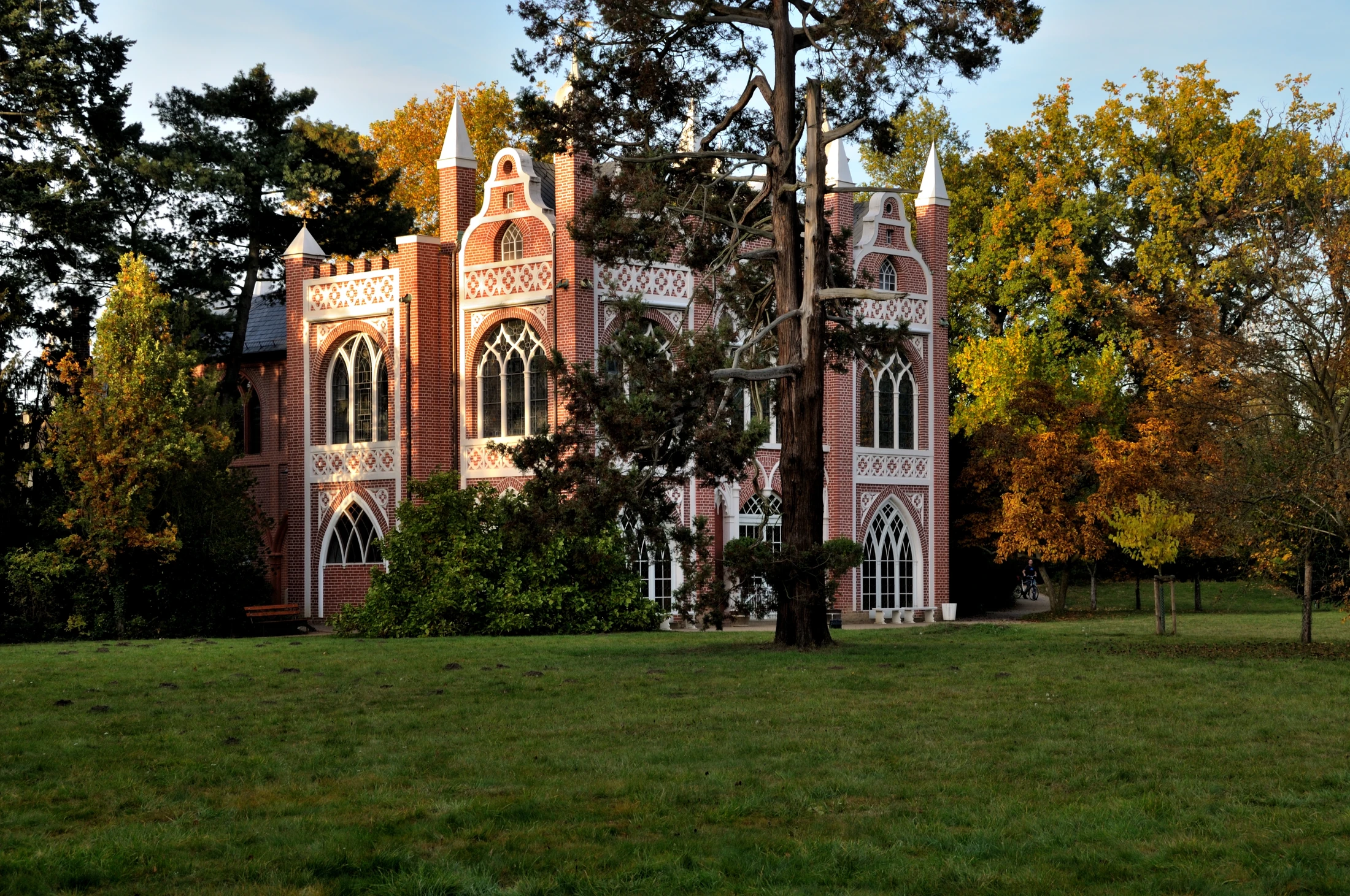 Red façade of the Gothic House among trees in Wörlitz Park in autumn