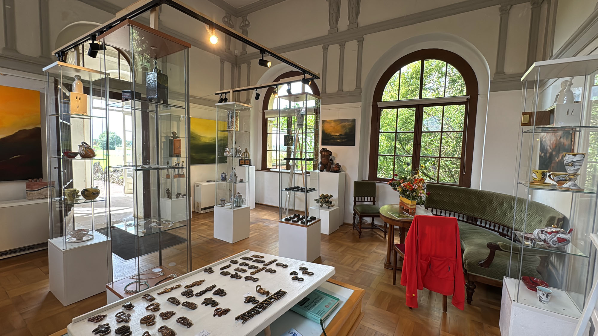 Blick in den Ausstellungsraum mit Vitrinen, Gemälden und Schmucktisch