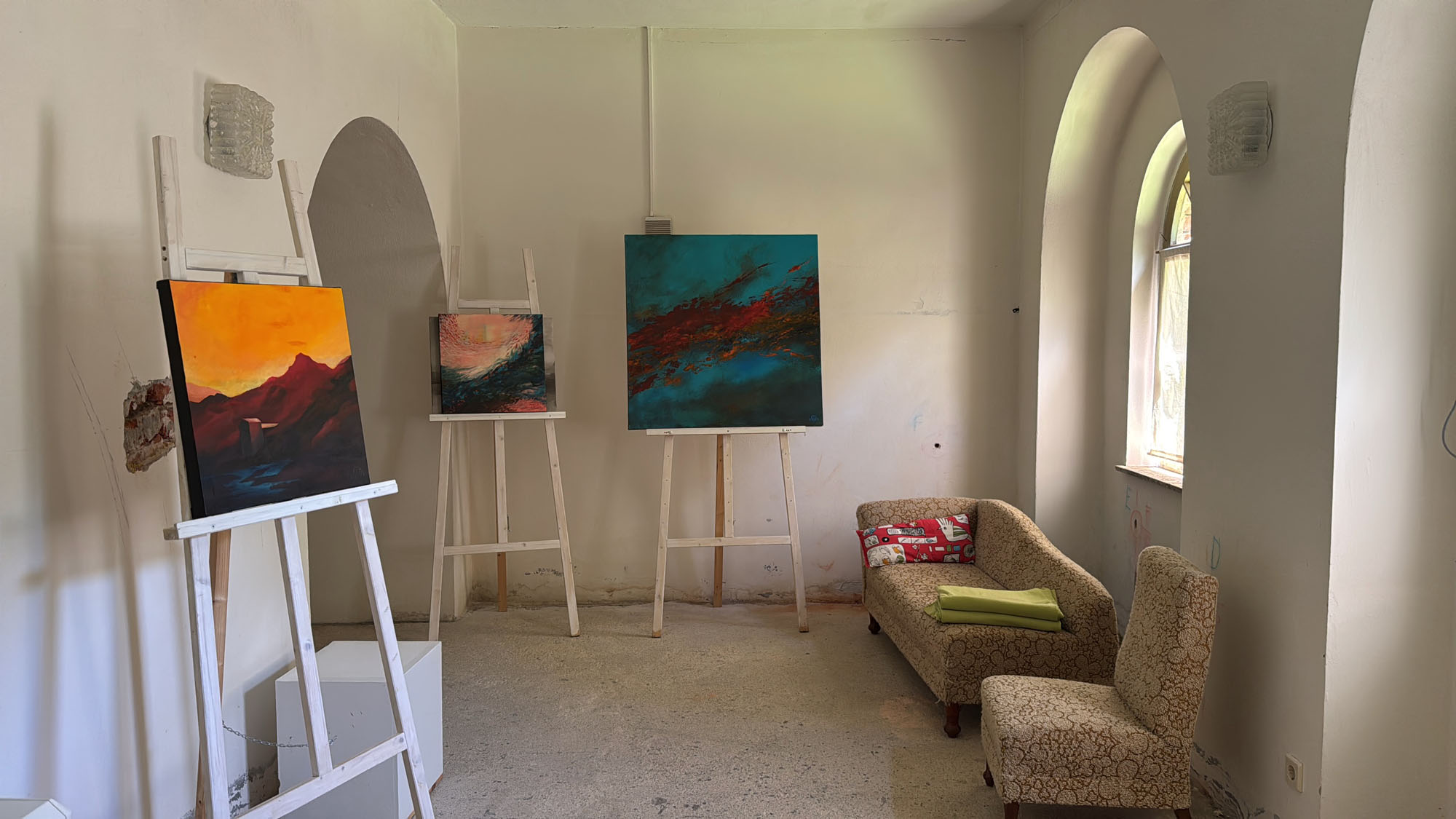 Drei Gemälde auf Staffeleien im Ausstellungsraum
